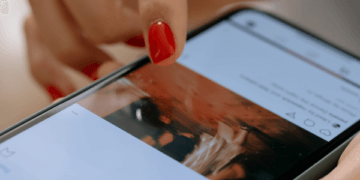 mulher com esmalte vermelho clicando na tela do celular