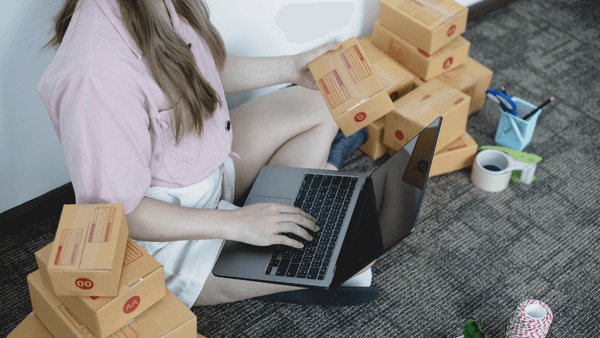 mulher com caixa no coloco inserindo produto no computador