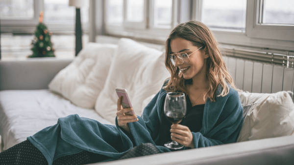 mulher com taça de vinho e celular na mão sorrindo