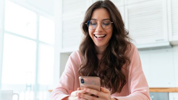 mulher feliz olhando para resultados de postagens no instagram pelo celular