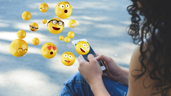 emojis saindo do celular de uma mulher
