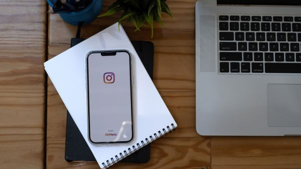 celular abrindo aplicativo móvel do instagram com notebook ao lado